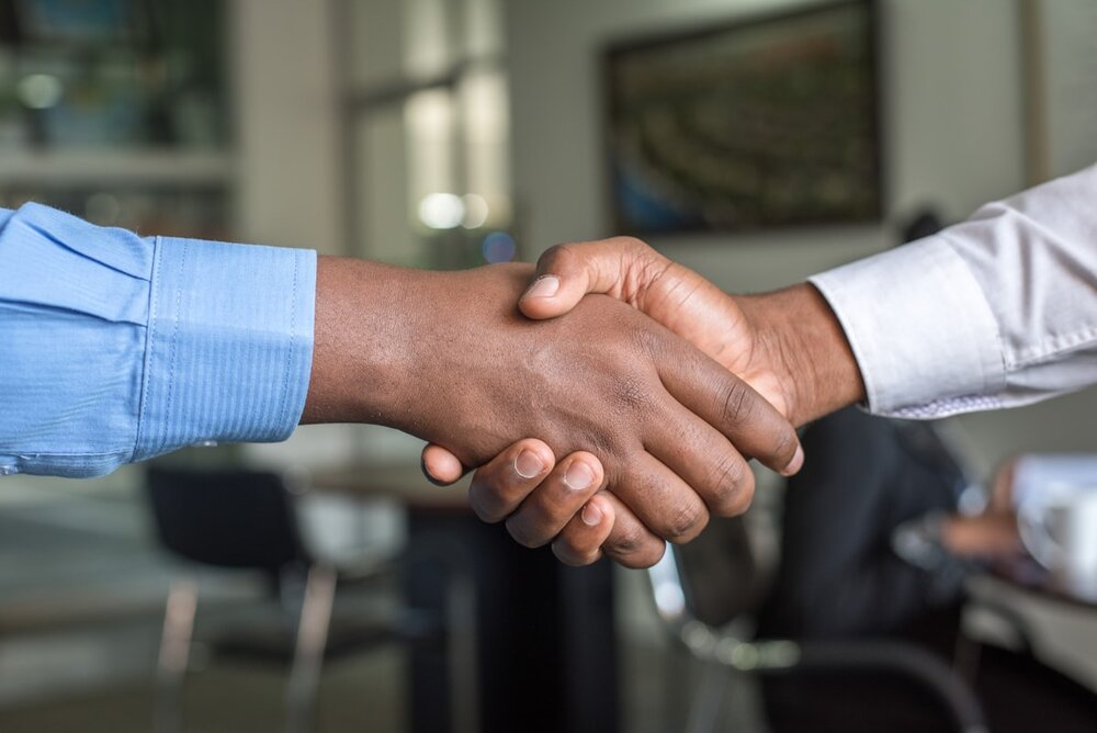 Manos unidas frente a un contrato, simbolizando resolución y acuerdo